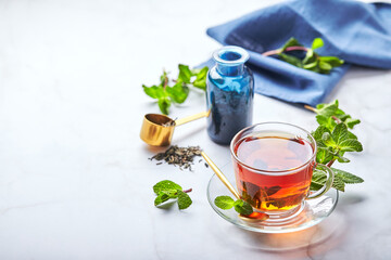 Black tea in glass transparent mug with mint leaves. Soothing tea, anti-stress
