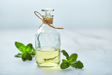 bottle with mint essential oil and green leaf on white background. Natual organic ingredients for cosmetics, skin care, body treatment. Beauty care concept