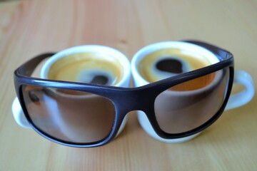 Two cups of coffee on the table and sunglasses.