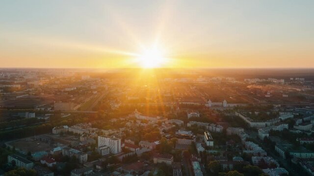 Aerial time lapse hyperlapse sunrise over big city, morning cityscape. Drone flight over industrial landscape. Bright sun beams on horizon. Belarus, Minsk at dawn overlooking city skyline