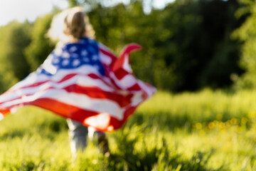 beautiful little blonde girl with the American flag in nature in the sunlight, photos in full focus