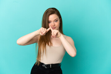 Fototapeta premium Teenager girl over isolated blue background making stop gesture with her hand to stop an act