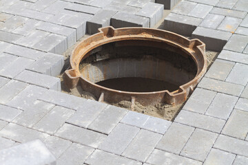 Naklejka premium Open dangerous manhole of a sewer well on the sidewalk at the house