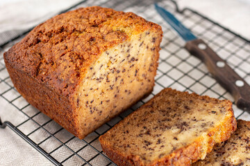 Sliced loaf of banana bread cupcake with poppy seeds on cooling wrack