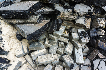 A fragment of paving stones and asphalt on a destroyed road. Dismantling of the old road surface on a city street. Close-up