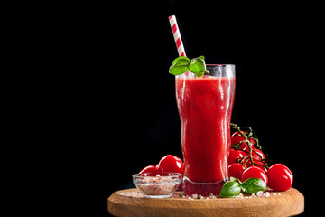 Glass of fresh tomato juice, basil and tomatoes on black background. With copy space