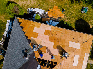 Roof construction repairman on a residential apartment with new roof shingle being applied - obrazy, fototapety, plakaty