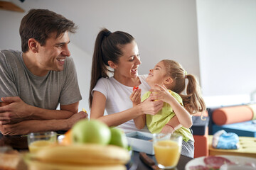 A little daughter enjoying a breakfast at home with her parents. Family, together, breakfast, home