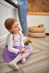 Obraz na płótnie Canvas An unsatisfied little girl sitting on the floor at home. Family, home, play