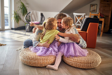 A young excited family in a hug while playing at home. Family, home, play