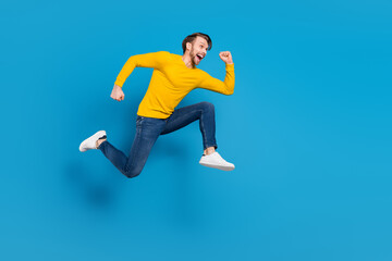 Fototapeta na wymiar Full length side profile body size of young guy jumping high running on sale isolated vivid blue color background
