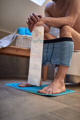 A young man sits on a toilet bowl in the bathroom and defecating. Toilet, need, home