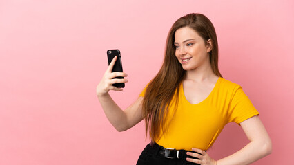 Teenager girl over isolated pink background making a selfie