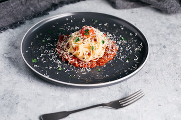 Spaghetti bolognese with tomatoes and parmesan on a vintage grey background