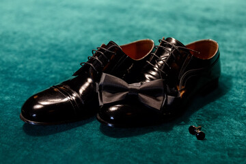 Black shoes and a groom's bow tie on a billiard table against a background of green cloth