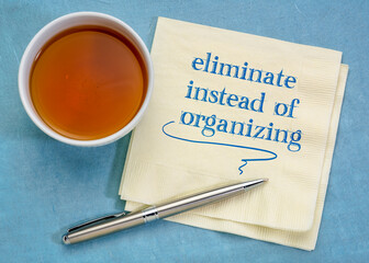 eliminate instead of organizing - handwriting on a napkin with a cup of tea, simplicity and decluttering concept