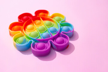 Rainbow pop it fidget toy on light pink background with copy space. Push bubble fidget sensory toy - washable and reusable stress relief toy. Antistress toy for children or adult. Mental health