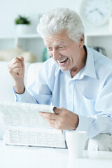 Senior man reading newspaper  at home