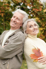 portrait of beautiful senior couple with leaves  in the park