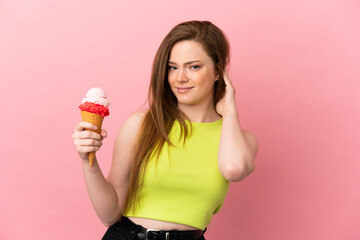 Teenager girl with a cornet ice cream over isolated pink background having doubts