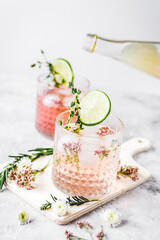 pink fresh cocktail with flowers and cut lime on stone desk background
