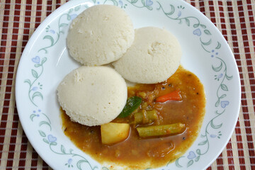 Wholesome South Indian breakfast. Three idlis and sambar on porcelain plate, top down view. Popular...