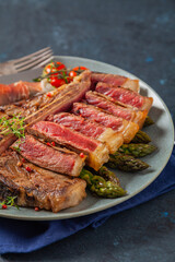 Grilled, medium-baked t-bone beef steak. Served with asparagus.
