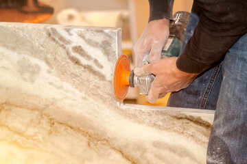 Man making vertical cut with electric hand saw during align marble kitchen countertop at...