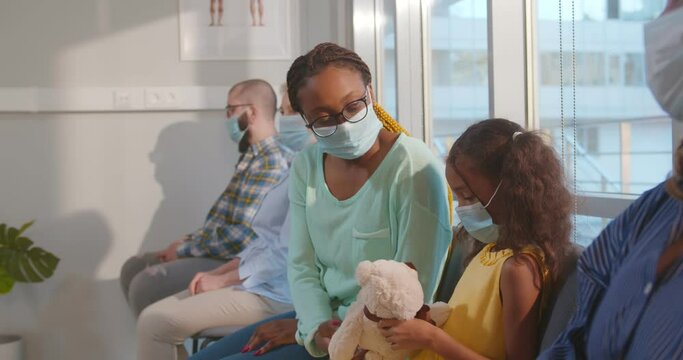 African doctor inviting patients in hospital waiting-room for coronavirus vaccination.