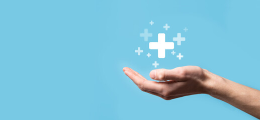 Male hand holding plus icon on blue background. Plus sign virtual means to offer positive thing like benefits, personal development, social network Profit,health insurance, growth concepts