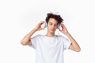 guy with curly hair and headphones white t-shirt light background close-up cropped