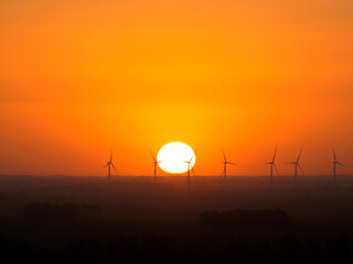 sunset in a field with windmills