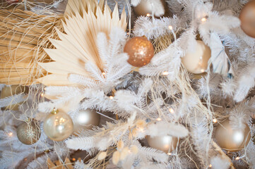White Christmas decoration with balls on fir branches with blurred background. White Christmas tree with beige Christmas balls and lights.