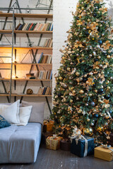 The Christmas tree is tall, decorated with golden balls and garlands, next to the sofa in the living room. Christmas tree in the interior.