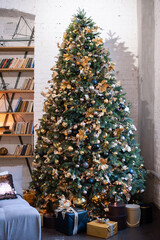 The Christmas tree is tall, decorated with golden balls and garlands, next to the sofa in the living room. Christmas tree in the interior.
