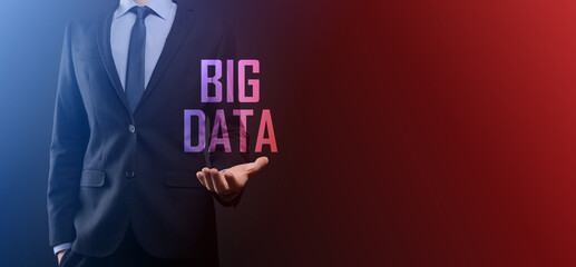 Businessman in a suit on a dark background holds the inscription BIG DATA. Storage Network Online Server Concept.Social network or business analytics representation