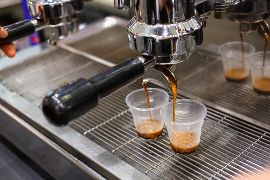 Caff&egrave; mentre scende da una macchina da caff&egrave; professionale in due bicchierini di plastica monouso trasparente