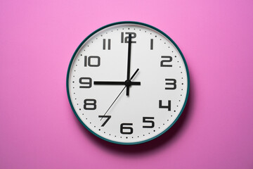 Retro clock at 9 o' clock on pink table background, vintage style