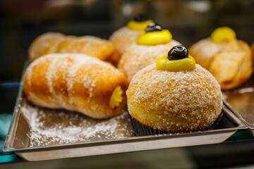 Brioche fritte ripiene di crema pasticciera e guarnite con crema pasticciera e ciliegie 