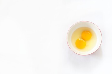 Top view of two raw eggs in bowl on isolated white background.