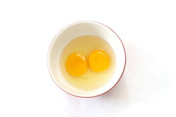 Top view of two raw eggs yolk in bowl on isolated white background.