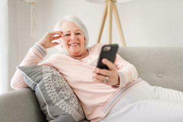 portrait of elderly woman sit on the sofa at home with cellphone
