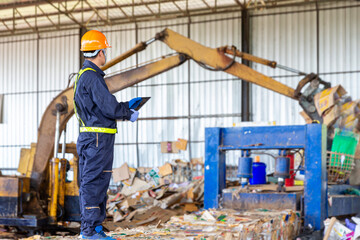 Engineer driving a loader in the recycling plant. Factory recycle workers are using a tablet to control work in the recycling plant. - obrazy, fototapety, plakaty