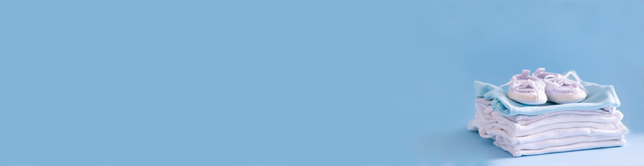 Clothes and shoes for a newborn in blue and white. Things for the little ones on a blue background. The concept of the birth of a new life and parenthood. Close-up selective focus