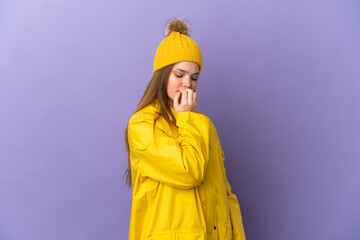 Teenager girl wearing a rainproof coat over isolated purple background having doubts