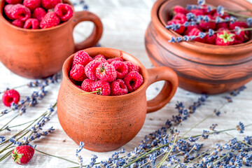 raspberry in pottery cup with lavander on wooden background