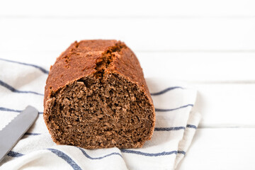 Home baked dark rye bread sliced in half on white background