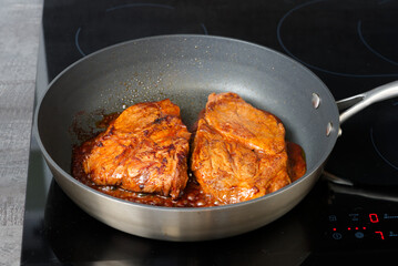 Pork steak with sauce fried in a frying pan at home
