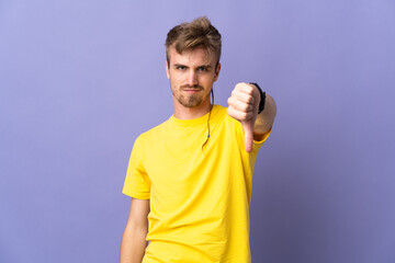 Young handsome blonde man isolated on purple background showing thumb down with negative expression