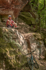 nice and active senior woman riding her electric mountain bike with full concentration on a rocks trail in the Pfaelzerwald forest near the city of Pirmasens in Rheinland-Pfalz, Germany
